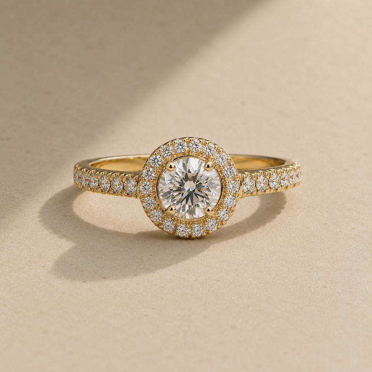Yellow gold halo diamond engagement ring with pavé band on warm beige background