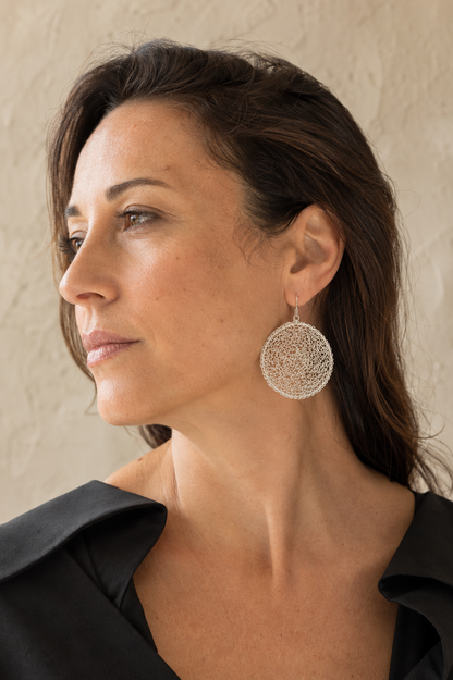 Model wearing large hand-crocheted Crochet Moon sterling silver earrings by JYOCO