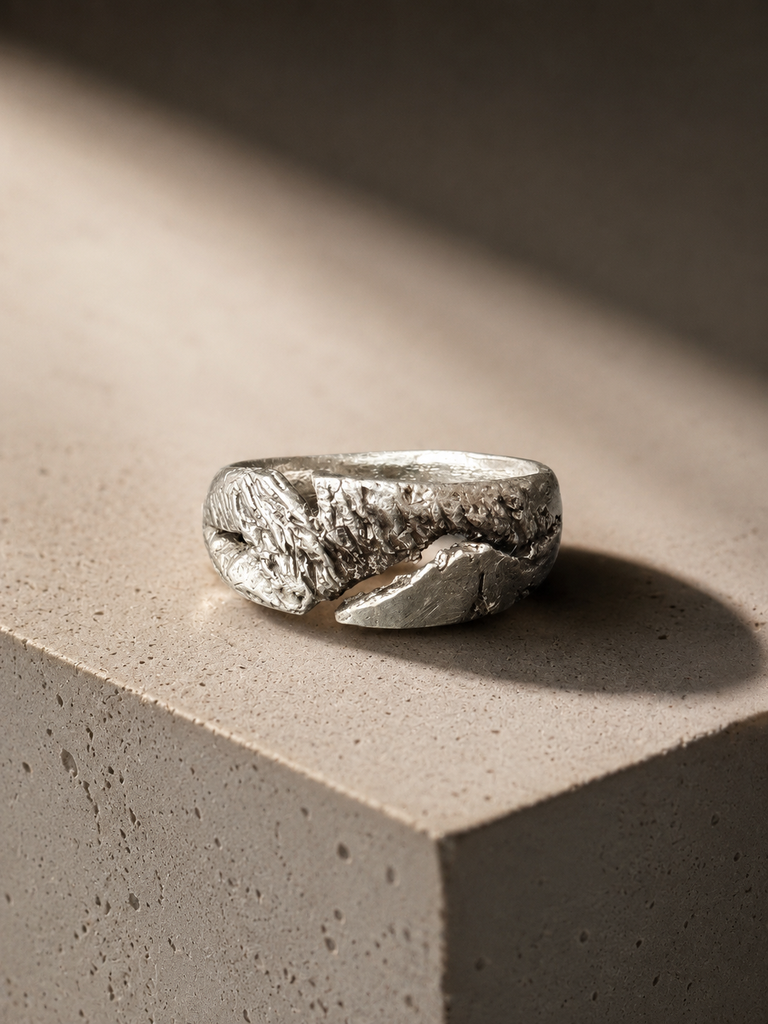Silver ring made by JYOCO with a textured design on a concrete surface