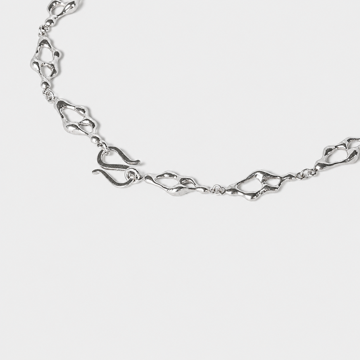 Sculptural silver necklace detali with organic openwork links arranged in a flowing circular composition