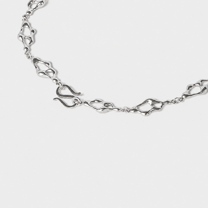 Sculptural silver necklace detali with organic openwork links arranged in a flowing circular composition