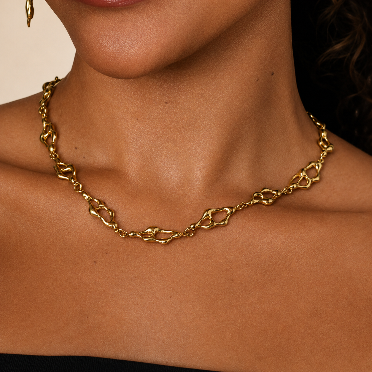 Gold chain necklace on a person's neck against a neutral background