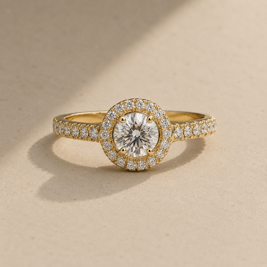 Yellow gold halo diamond engagement ring with pavé band on warm beige background