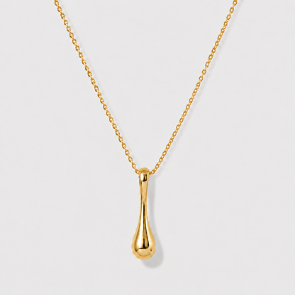 Minimal sculptural gold drop pendant necklace on delicate chain against soft neutral background