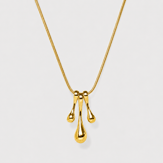 Gold necklace with a three-drop pendant on a light gray background