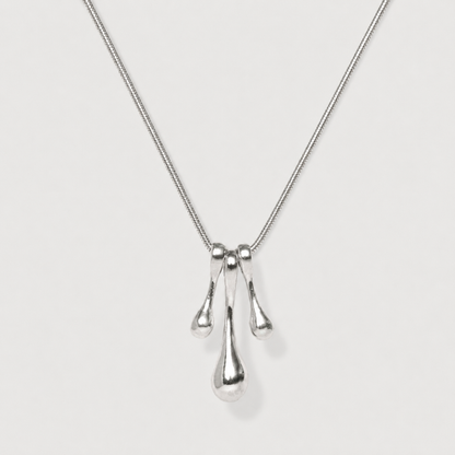Silver necklace with three droplet pendants on a light gray background