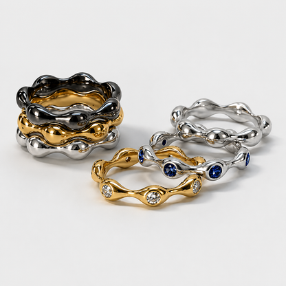 Three gold, silver, and two-toned rings with gemstones on a light gray background