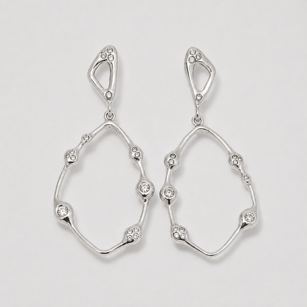 Pair of silver earrings with diamond-like stones on a light gray background
