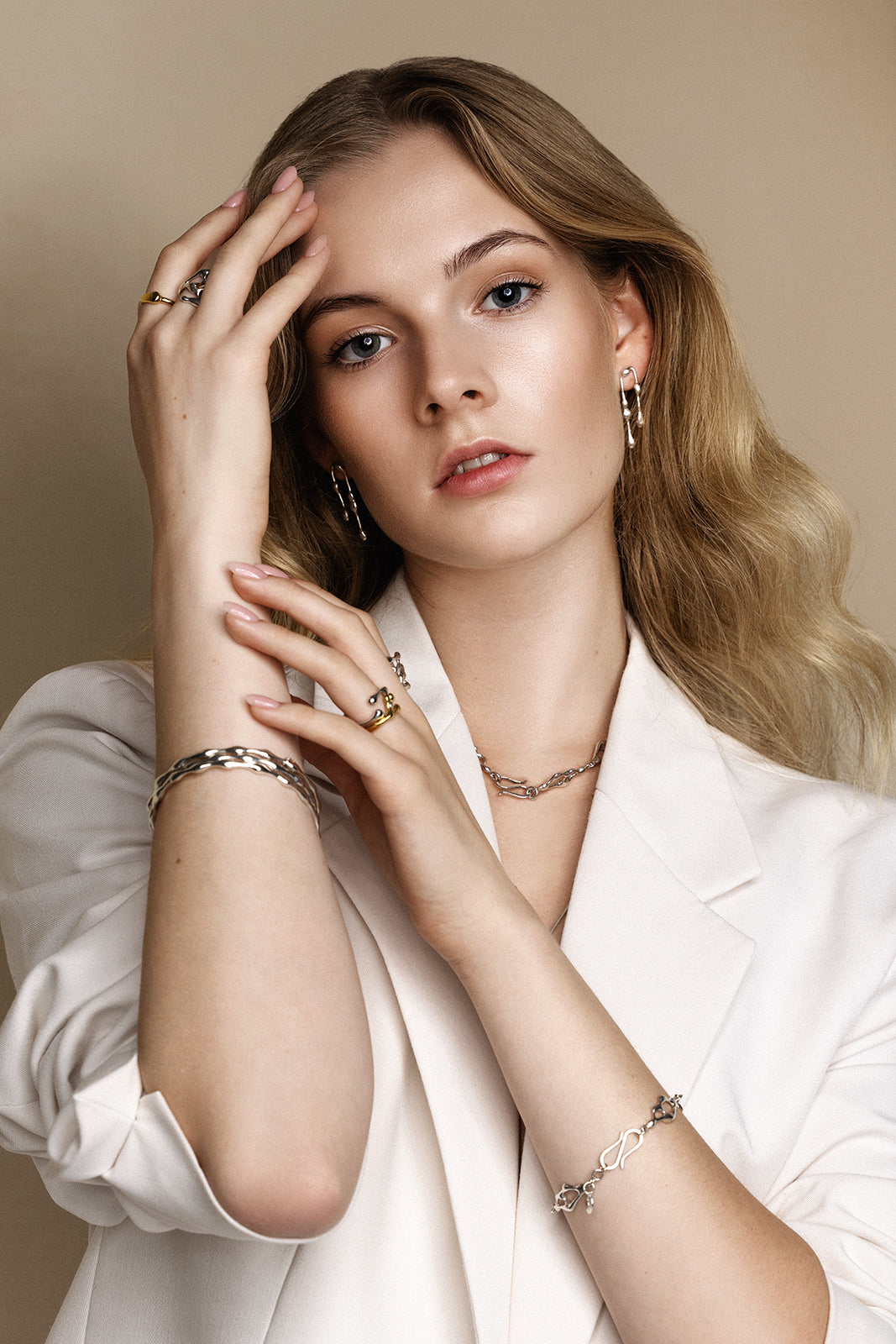 Woman wearing multiple pieces of jewelry against a neutral background