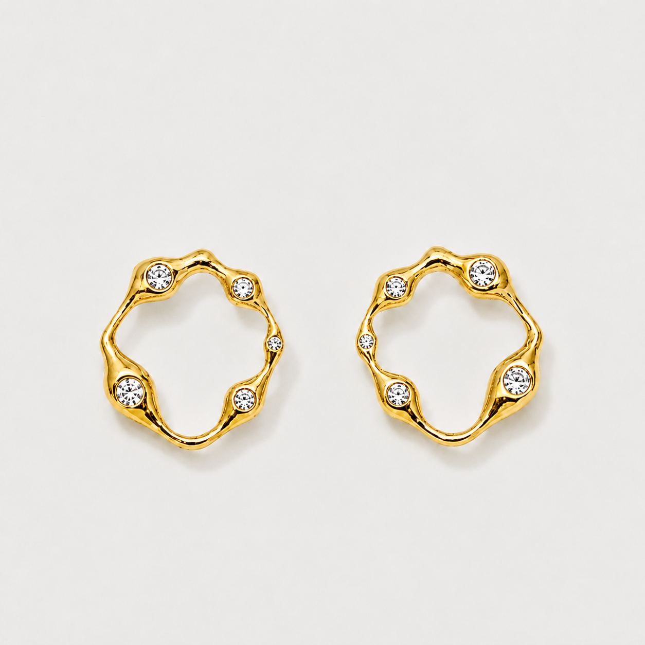 Gold hoop earrings with embedded crystals on a light gray background