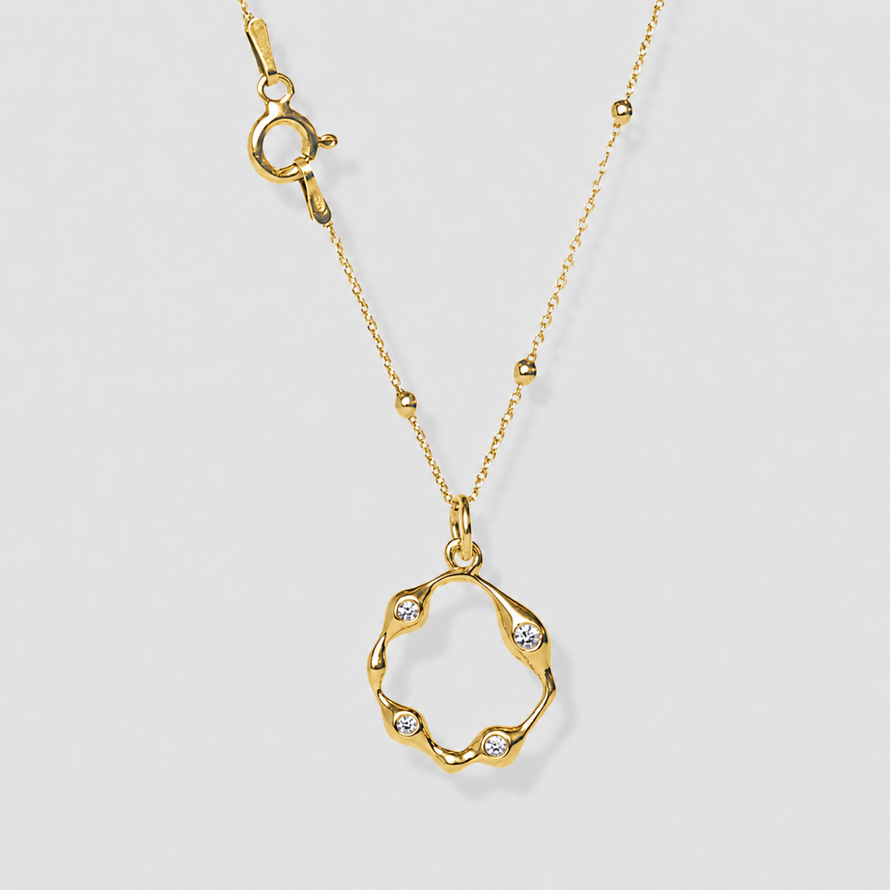 Gold necklace with a unique pendant on a light gray background