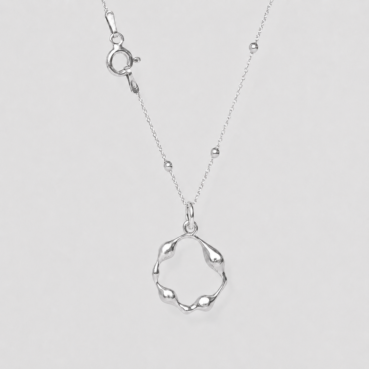Silver necklace with a unique pendant on a light gray background
